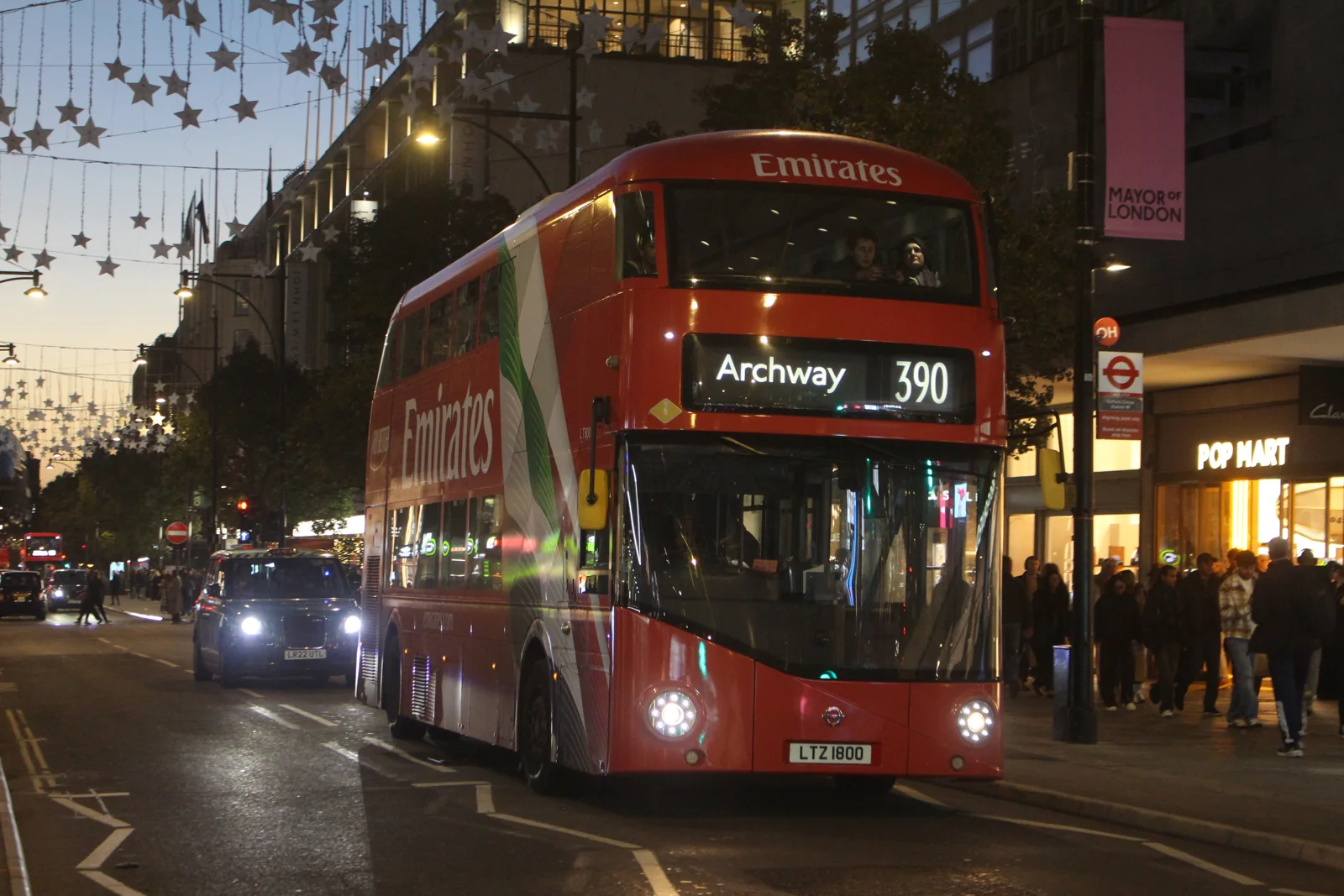 A red route 390 bus and a black cab on Oxford Street at dusk on the last evening before traffic was banned
