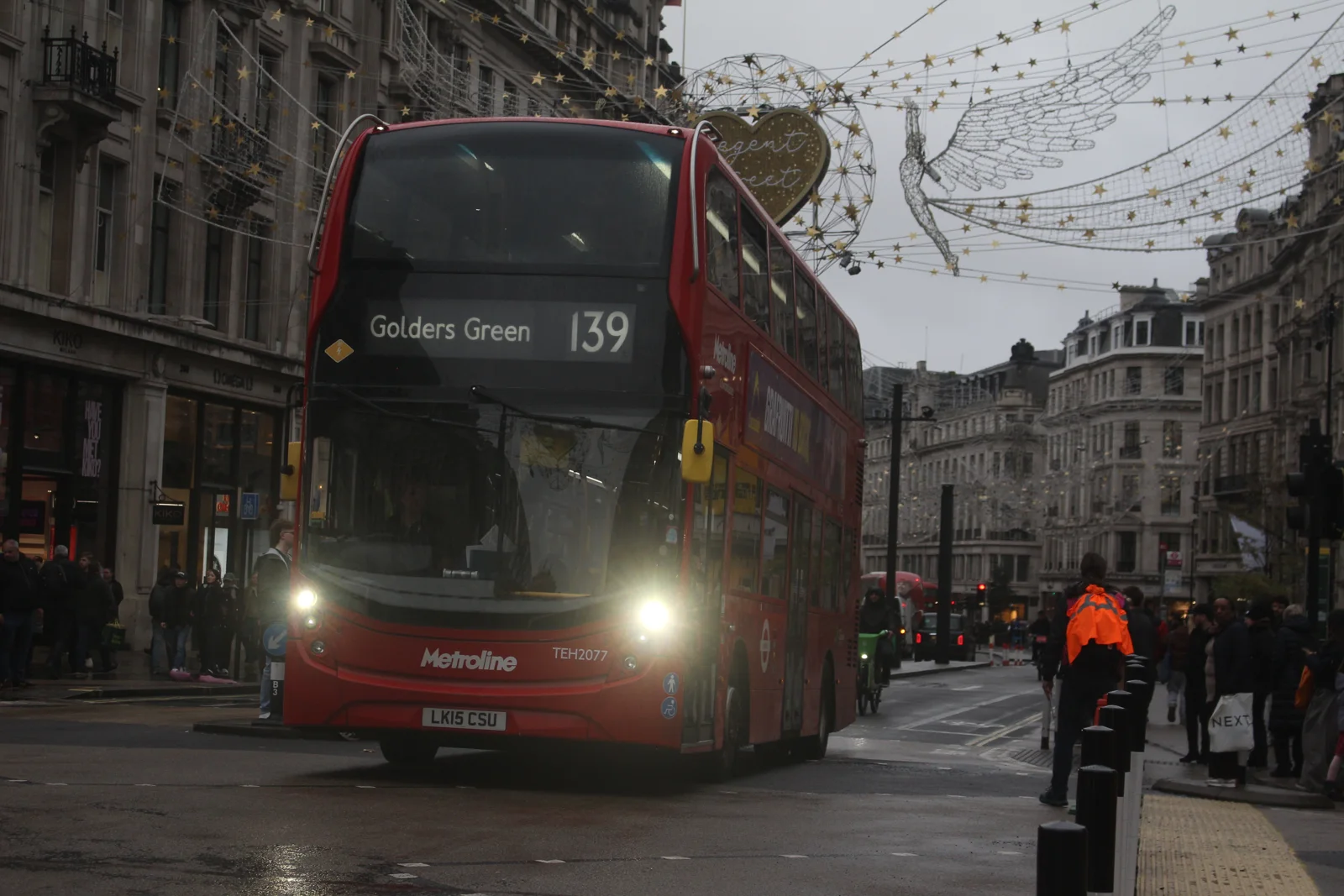 A TfL marshal in orange hi-vis by the new bollards at Oxford Circus as a diverted 139 bus crosses on Regent Street